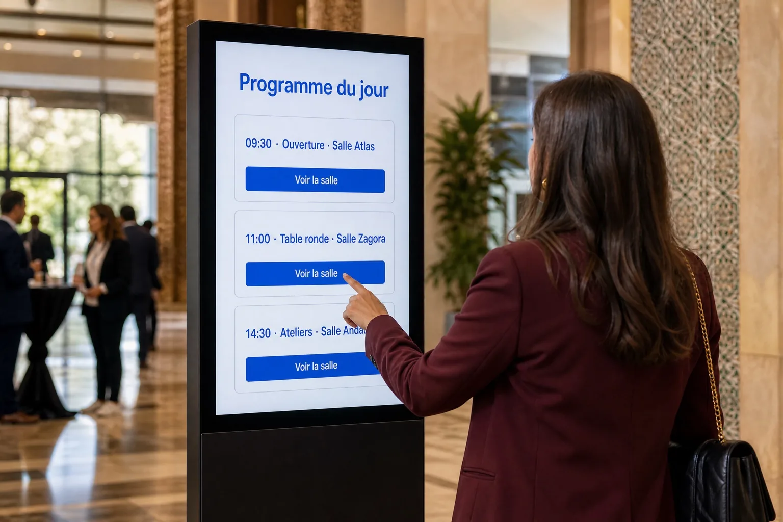 Gros plan : le programme du jour et les salles sur l’écran d’un totem.